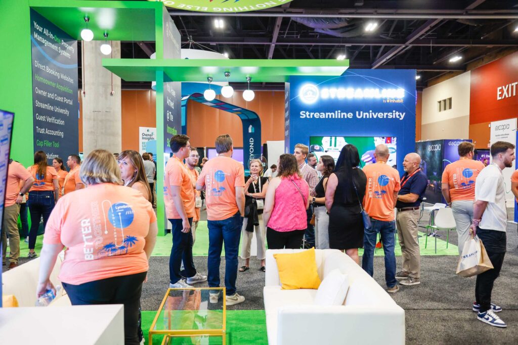 Streamline team in orange shirts talking with attendees at the Streamline booth at VRMA International 2024
